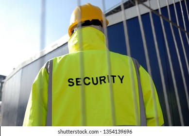 Security Guard Behind Metal Fence. 
