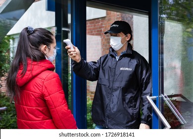 Security Guard Checking Temperature At Building Entrance