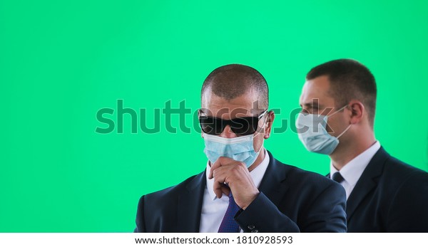 Security\
guard listening to his earpiece on event. Police man with surgical\
mask talking on event during alarm state in covid 19 coronavirus\
crisis. secret service guard. private\
bodyguard.