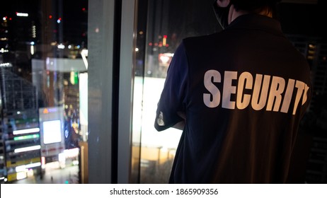 Security Guard Looking Down At The City At Night