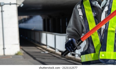 A security guard man with a red stick. - Shutterstock ID 2121112577