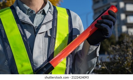 A Security Guard Man With A Red Stick.