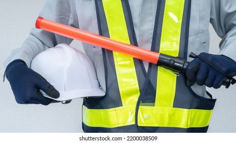 A Security Guard Man With A Red Stick.