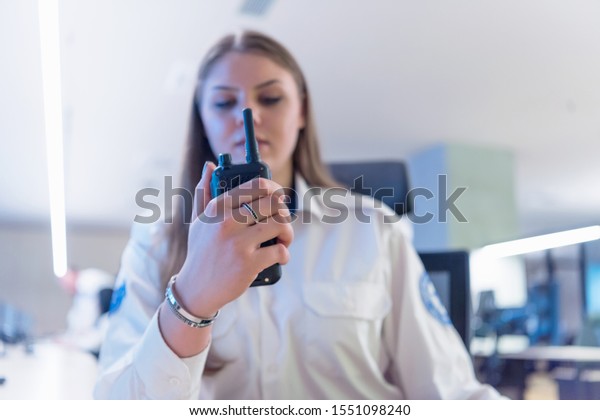 Security guard\
monitoring modern CCTV cameras in surveillance room. Female\
security guard in surveillance room. Female security guard holding\
portable radio in hand at\
workplace.
