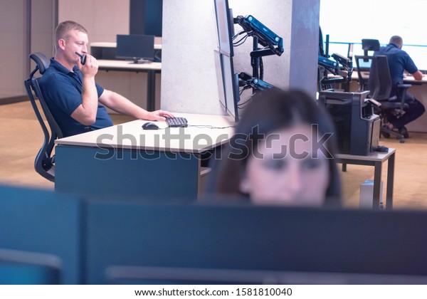 Security guard\
monitoring modern CCTV cameras in surveillance room.Male security\
guard in surveillance room. Male security guard holding portable\
radio in hand at\
workplace.