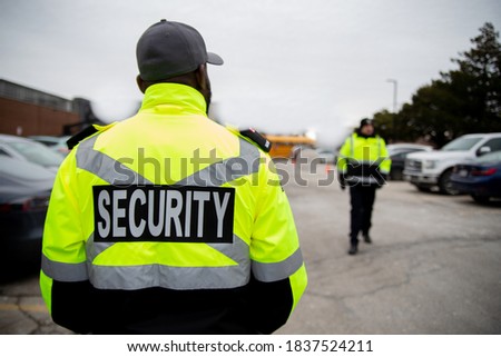 Security guard patrolling around parking lot area under cloudy sky