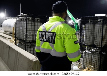 A security guard is patrolling a commercial storage area at night.