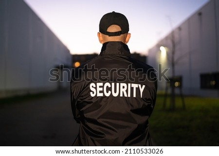 Security Guard Securing Building At Night In Alley