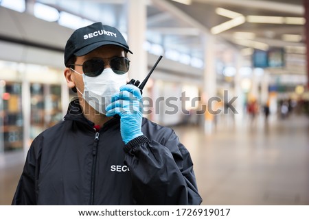 Security Guard Standing In Face Mask In Airport Terminal