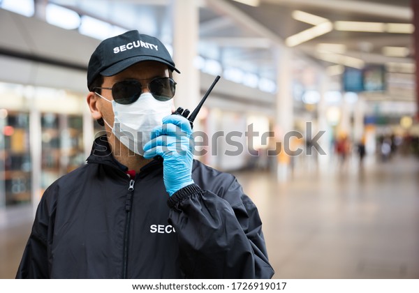 Security\
Guard Standing In Face Mask In Airport\
Terminal