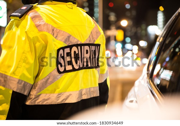 Security guard standing next to security car at\
night city