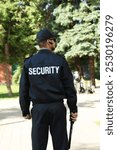 Security guard in uniform with baton outdoors, back view