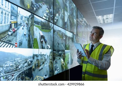 Security guard using digital tablet in security control room with video wall
