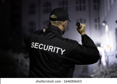 Security Guard Walking Building Perimeter With Flashlight At Night - Powered by Shutterstock