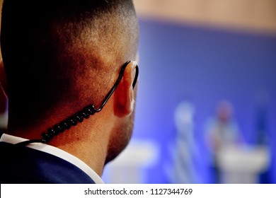 A Security Guard wears an ear headset during a government summit meeting. - Powered by Shutterstock