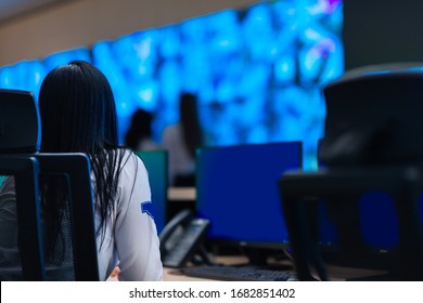 Security guards standing in front of a large CCTV monitor at the main control room while reading and discussing plans