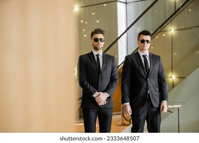 security guards, two handsome men in formal wear and sunglasses, bodyguards on duty, safety measures, vigilance, black suits and ties, private security, strong men