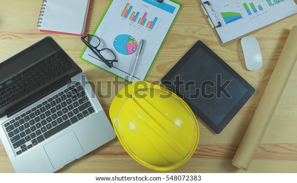 security helmet and blueprint paper\
construction drawing plan near laptop computer,Architect working in\
office,Engineering tools on desk at site\
project