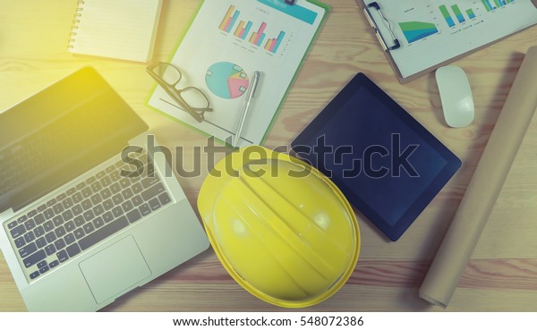 security helmet and blueprint paper\
construction drawing plan near laptop computer,Architect working in\
office,Engineering tools on desk at site\
project