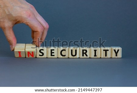 Security or insecurity symbol. Businessman turns wooden cubes, changes words insecurity to security. Beautiful grey background. Business, security or insecurity concept. Copy space.