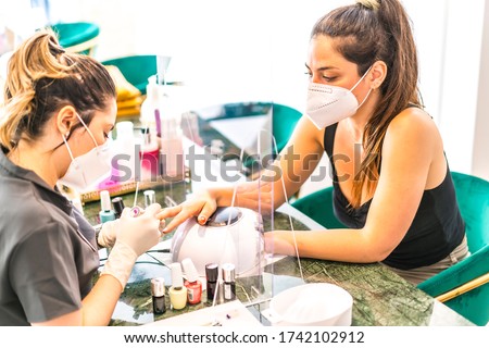With security measures and face mask painting colored nails of the client. Reopening after the corod-19 pandemic. Manicure and Pedicure Salon. Coronavirus