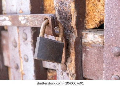 Security No Access Concept. Rusty Metal Padlock Locked On Steel Rod Forbid, Even It Is Old, The Entrance In The Building. Weathered Vintage Damaged Closed Exterior Door Provides Safety And Privacy.