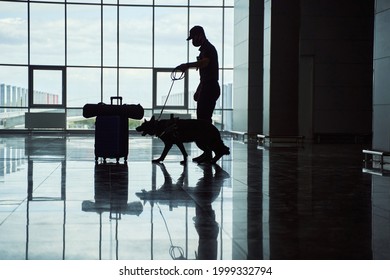 Security officer with detection dog checking luggage at airport