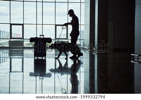 Security officer with detection dog checking luggage at airport
