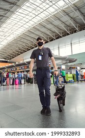 Security Officer With Detection Dog Walking Down Airport Terminal