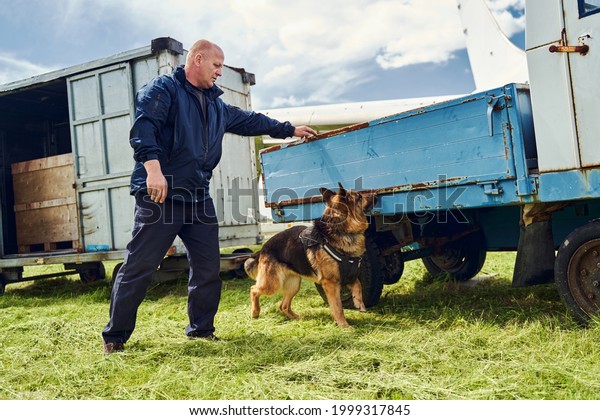 Security officer and drug detection dog\
checking truck at\
aerodrome