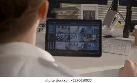 Security officer monitors CCTV cameras in coworking office on digital tablet computer. Modern program showing footage of surveillance cameras on screen. High tech security. Concept of social safety.
