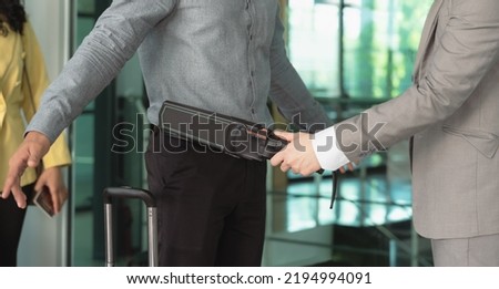 Security officer using a metal detector on a male passenger at airport boarding gate