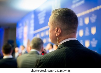 Security On Public Event. Secret Guard Service. Private Bodyguard With Earpiece Standing Among Crowd. Safety Of Govern And Business Meeting. Secret Service Agent Listening To His Earpiece, Side.