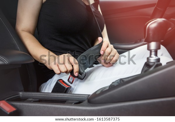 Security on the road. Woman driver fastening safety\
belt sitting inside\
car