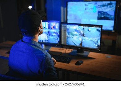 Security operator controls CCTV cameras in office at night. Modern security system and social safety concept.