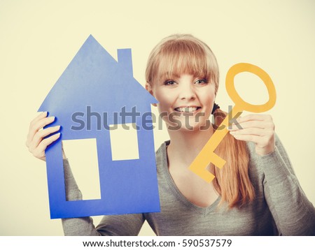 Security safety home ownership concept. Young blonde lady holding symbols. Cheerful girl showing house key cutouts.
