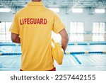 Security, safety or lifeguard by a swimming pool to help rescue the public from danger or drowning in water. Back view, trust or man standing with a lifebuoy ready with reliable assistance or support