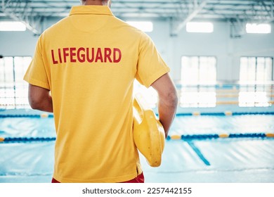 Security, safety or lifeguard by a swimming pool to help rescue the public from danger or drowning in water. Back view, trust or man standing with a lifebuoy ready with reliable assistance or support