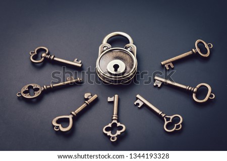 Security or secret protection concept, vintage brass padlock surrounded by multiple keys on a dark black background, internet hacker or cyber safety metaphor.