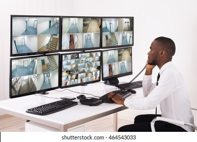 Security System Operator Talking On Phone While Looking At CCTV Footage