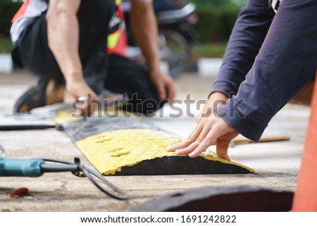 Security team installing safety road speed breaker or hump by using drill and hammer