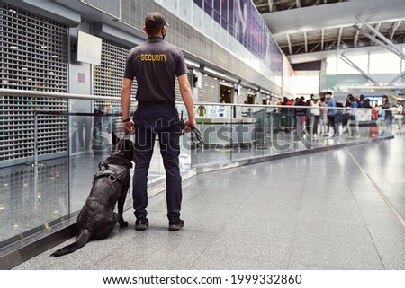 Security worker with detection dog patrolling airport terminal