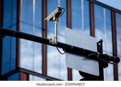 Securty traffic camera over an intersection, facade of a modern office building in the background. Traffic intersection signal surveillance camera. Surveillance camera for traffic violations