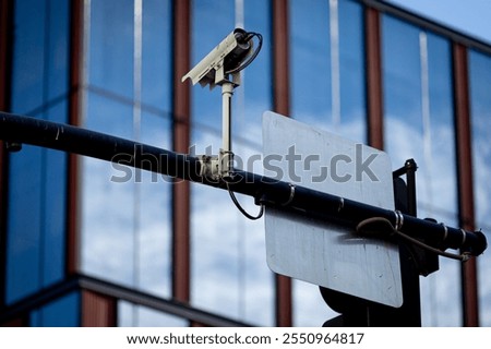 Securty traffic camera over an intersection, facade of a modern office building in the background. Traffic intersection signal surveillance camera. Surveillance camera for traffic violations