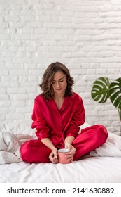 sed tired angry woman in pajamas sitting on the bed in the morning and holding empty cup . bad morning