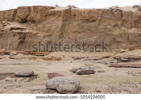 Sedimentary sand and rocks on the shore of sea of Cortez, San Felipe, Mexico, sandy rocky beach with huge layers of piled dust dirt sand stone and rocks cliff promontory, texture and grit 