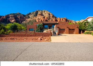 Sedona, Arizona USA - April 25, 2017: Typical modern adobe style architecture desert home with majestic red rock formations in the background in popular Sedona.