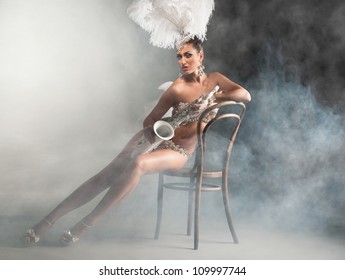 Seductive dancer with saxophone sitting on the chair