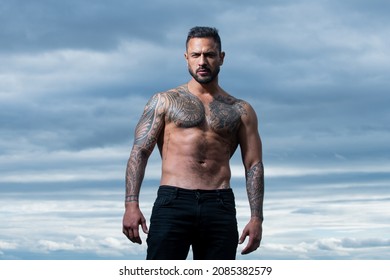 Seductive face of a sexy man. Macho looking confident. Outdoor male portrait on dramatic sky.