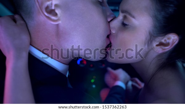 Seductive lady and handsome man kissing in\
car, couple having date,\
temptation